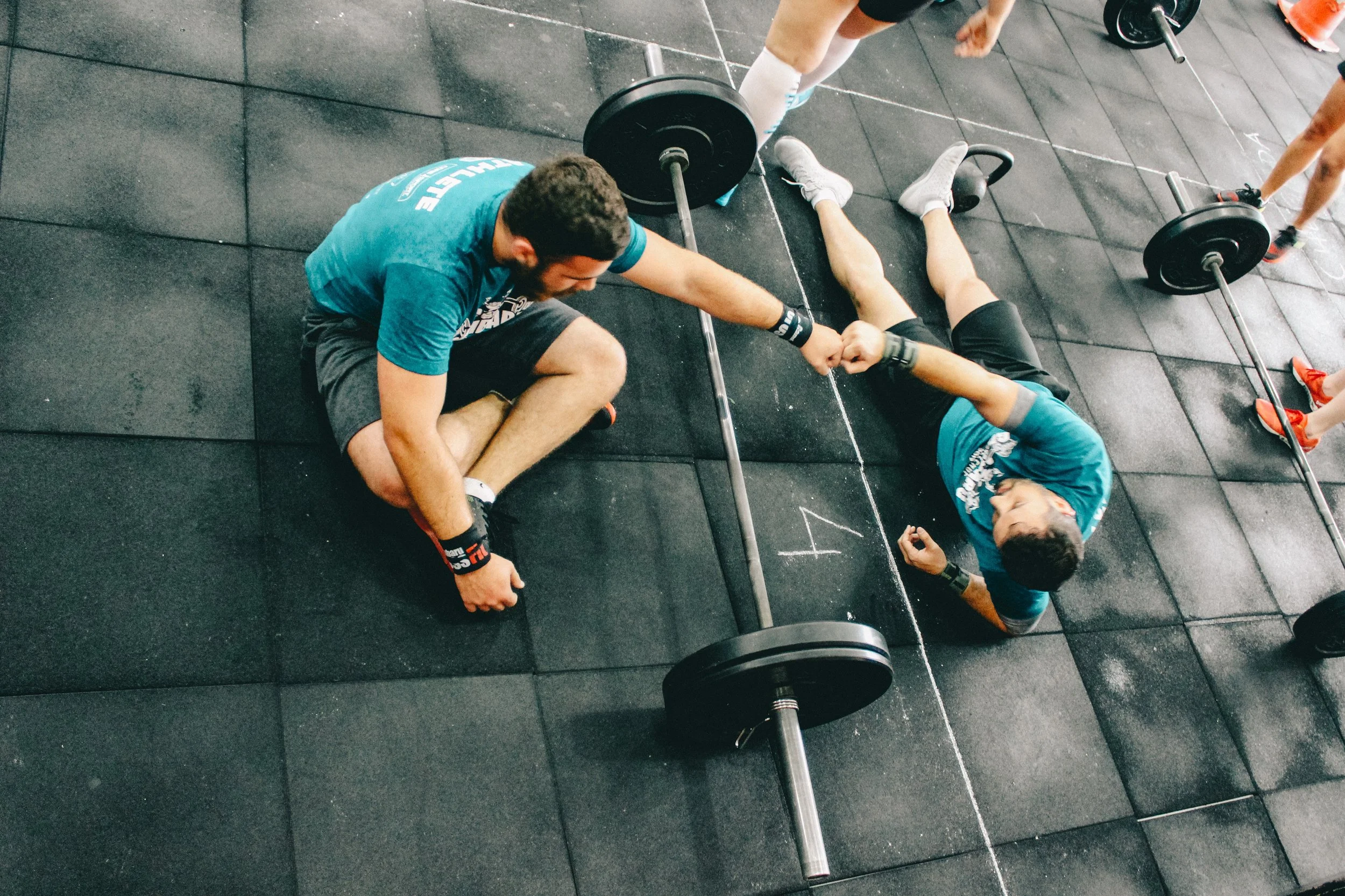 Athletes training with a barbell in a gym