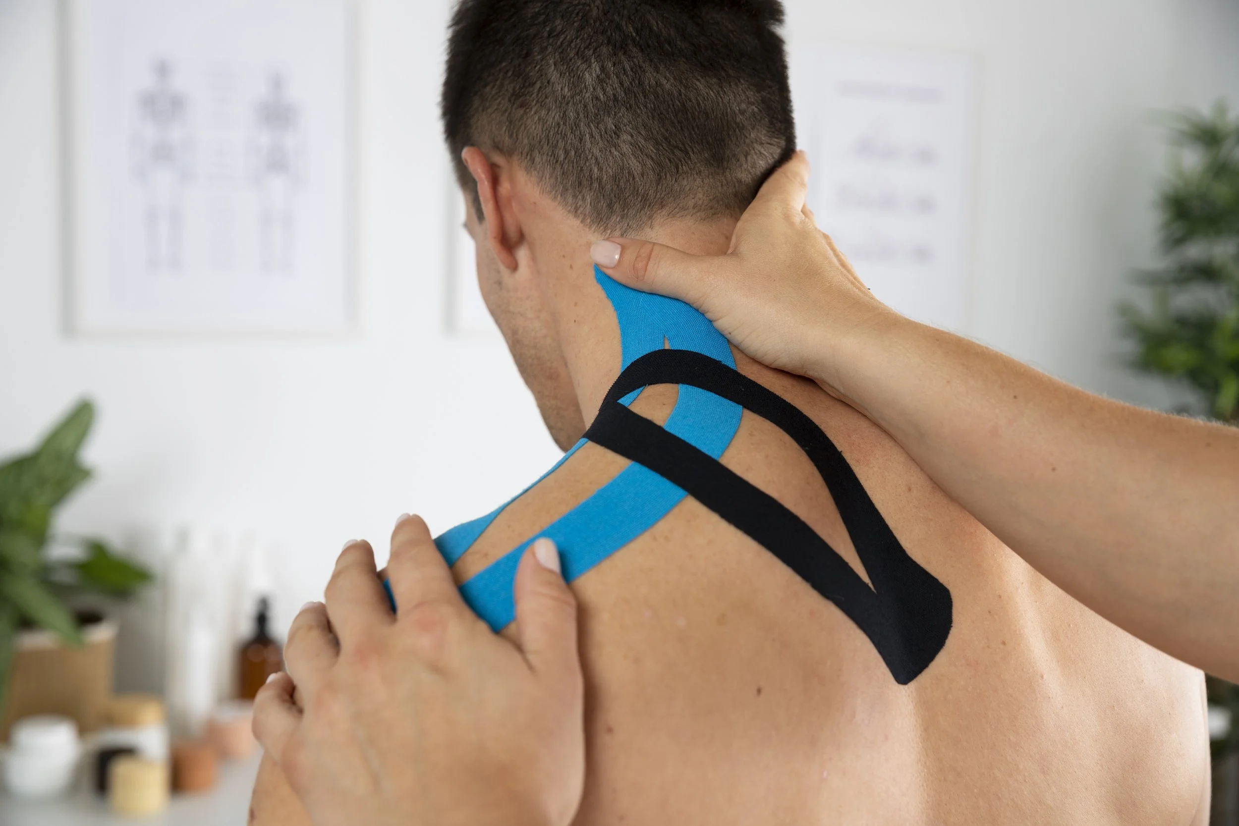 A physiotherapist applying kinesiology tape to a patient's shoulder